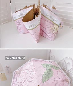 Detail of pink floral umbrella with hand-painted flower pattern and elegant golden hook handle