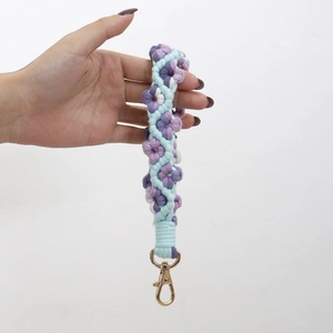 Detail of handmade woven floral keychain with purple and blue yarn and gold clasp