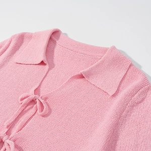 Detailed view of pink knitted top featuring a classic collar and elegant front tie bow