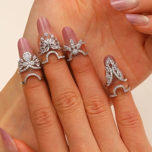 Close-up of four silver fingertip nail rings set with cubic zirconia in crown and snowflake shapes