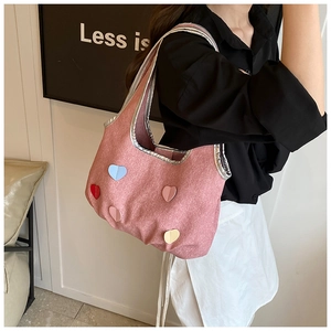 Gros plan sur un sac seau rose avec patchs cœurs colorés et bordure argentée