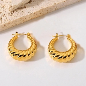 Golden twisted croissant hoop earrings in stainless steel on a white surface