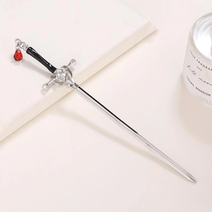 Silver sword hair pin with red gemstone pendant placed on a book for a vintage look