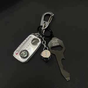 Detail of silver carabiner, thermometer, dice, and black bottle opener tool on dark texture
