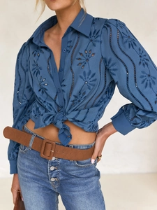 Detail of navy blue cardigan featuring intricate floral eyelet embroidery and hollow out texture