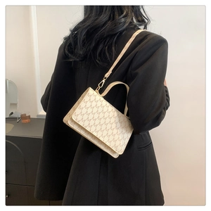 Detailed view of cream crossbody bag with letter print and golden twist lock closure