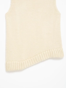 Detailed view of the ribbed knit fabric and asymmetrical hemline of the cream vest