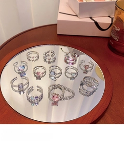 Exquisite assortment of silver rings with colorful heart-shaped zircons on a round mirror