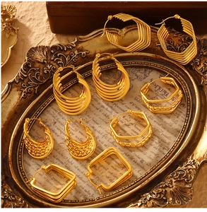 Detailed view of layered geometric gold earrings set on a vintage decorative tray
