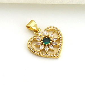 Macro detail of a golden heart pendant with a green gemstone flower and zircon accents