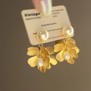 Vintage gold flower stud earrings with freshwater pearls shown in a handheld view