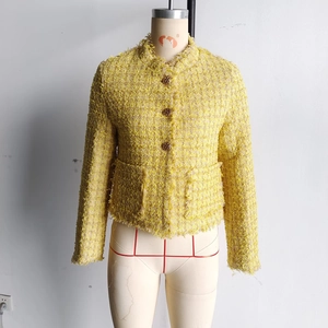 Detail of yellow tweed jacket featuring gold embossed buttons and frayed fringe edges