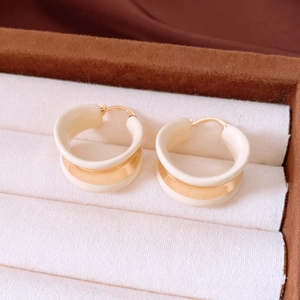 Detailed view of 18k gold plated cream enamel hoop earrings in a luxury jewelry box