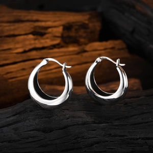 Minimalist U-shaped geometric silver earrings on a textured charcoal background