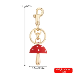 Detail van een rode paddenstoel sleutelhanger met witte steentjes en gouden haak