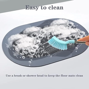 Detail showing the easy cleaning process of a grey oval diatom mud bath mat with a brush