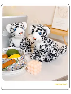 Close-up of two realistic white snow leopard plush toys in a cozy home office setting
