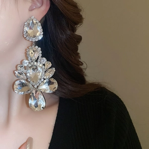 Close-up of large water drop rhinestone earrings worn on a model with silver plating