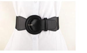 Close-up of black elastic waist belt with large round faux leather buckle on white shirt