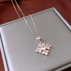 Close-up of rose gold flower pendant with zircons on a gray silk jewelry box