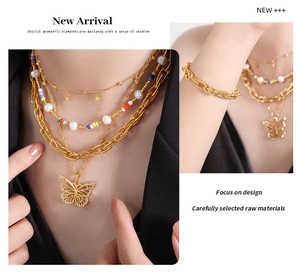 Detail of layered gold titanium steel necklace featuring a butterfly charm and pearls
