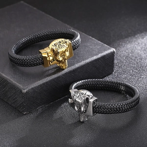 Detailed close-up of woven leather bracelets with silver and gold wolf head clasps