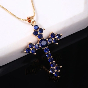 Golden cross necklace featuring deep blue round-cut crystals in a claw setting