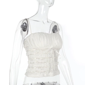 Detail of white lace camisole top featuring ruffled textures and a delicate center bow
