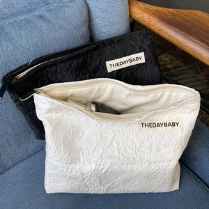 Detail of black and white rose jacquard toiletry bags on a sofa with textured fabric