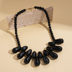 Detail of chunky black teardrop pendants on acrylic bead necklace with gold clasp