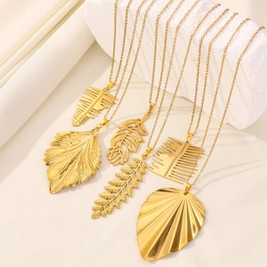 Detailed view of six gold leaf pendant necklaces displayed on a white textured stone