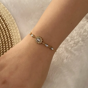Vue détaillée d'un bracelet cœur doré avec zircons porté au poignet d'un mannequin
