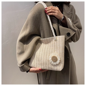 Detail of beige woven shoulder bag with rope strap and floral sunflower charm