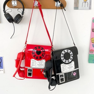 Detail of creative vintage telephone crossbody bag in shiny red and black finish