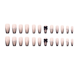 French nude coffin press-on nails with black V-tips, ribbon bows and silver rhinestones