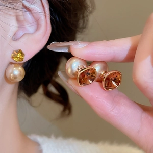 Detailed view of 18K gold plated amber crystal and pearl earrings worn by a model
