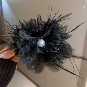 Detailansicht einer schwarzen Organza-Blume Haarklammer mit großer Perle auf Netzgewebe