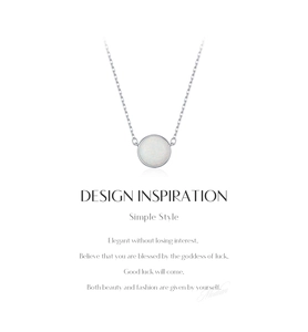 Macro detail of silver O-chain necklace with a round white opal pendant on white background
