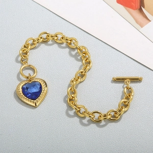 Detailed macro view of gold textured link bracelet with heart blue stone and toggle clasp