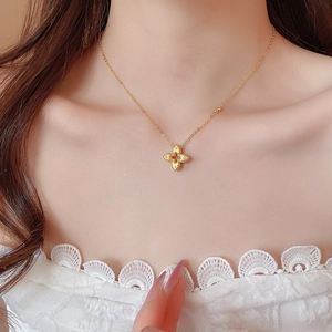 Close-up of a gold hollow flower pendant necklace with zircon on a model neck