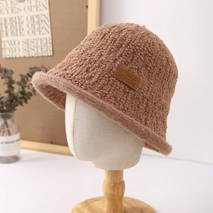 Detail of a brown fuzzy bucket hat with a leather 'Handmade' label on a mannequin