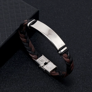 Close-up of black and brown braided leather bracelet with polished metal plate and clasp