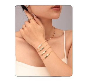Close-up of gold MOM bracelet with heart zircon and matching earrings on a model