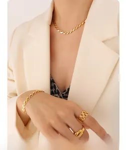 Detail eines vergoldeten Schmucksets mit hohlen Herzmotiven getragen zu einem beigen Blazer