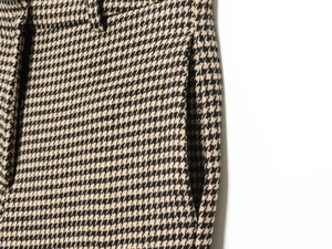 Close-up of houndstooth plaid trousers showing waist detail and side pocket texture