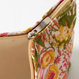 Macro view of floral embossed fabric and silver metal zipper on the large cosmetic bag