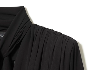 Detail view of elegant pleated shoulder design and soft chiffon fabric on a black blouse