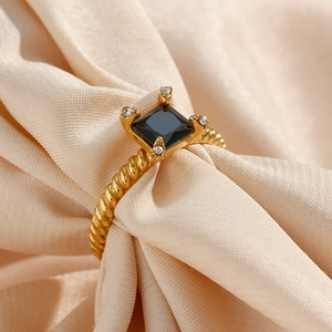 Macro detail of a 18K gold twist ring featuring a square black zircon and side diamonds
