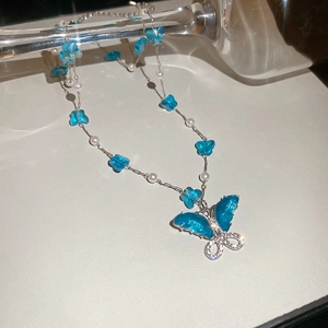 Detalle del collar con colgante de mariposa azul con perlas de vidrio y detalles de diamantes