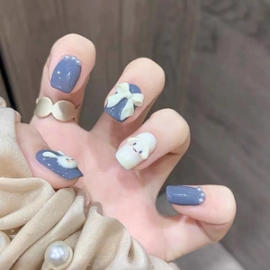 Detail of handmade press-on nails featuring 3D bow, pearls, and cute blue puppy charms